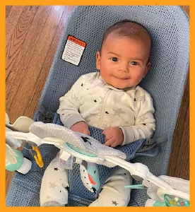 2 month old baby in a rocker wearing a star onesie
